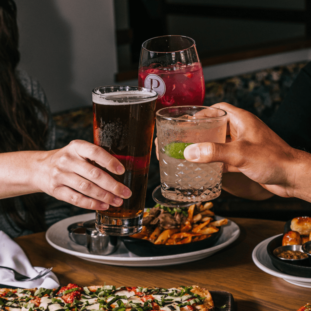 Three friends raising a Berry Bliss Lemonade, beer and Paloma together at Pinstripes.